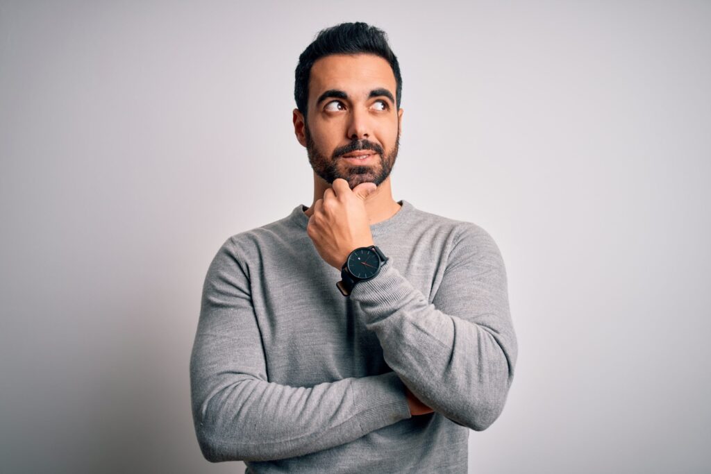 Man in a grey shirt standing and thinking about dental check-up
